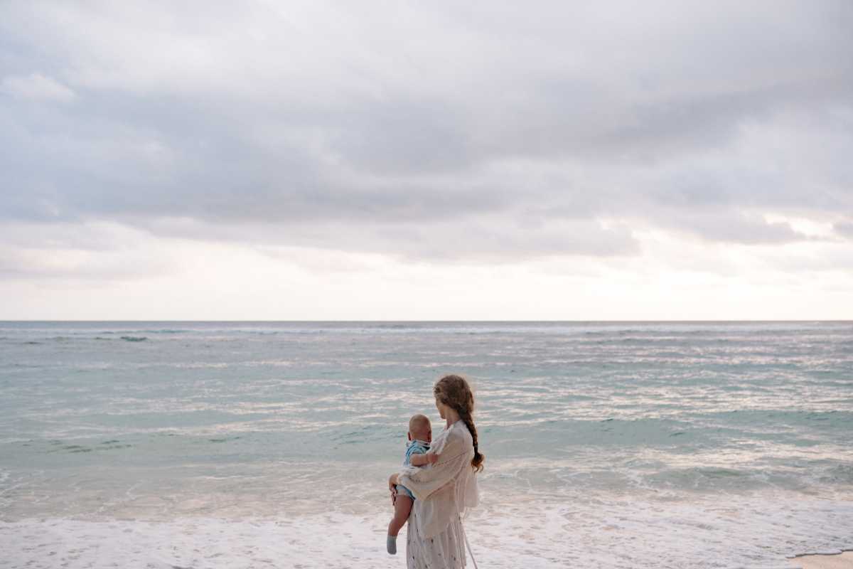 Famiglia con bambini piccoli che gioca sulla spiaggia dorata di Tropea, mare limpido e fondale basso, clima rilassato, atmosfera vacanziera