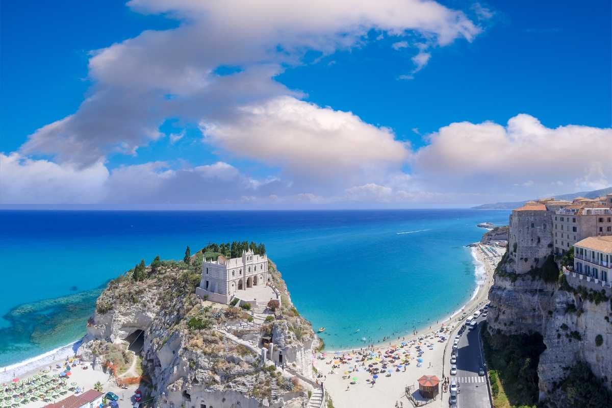 Scorcio ravvicinato della Spiaggia dell’Isola a Tropea, sabbia bianca, mare trasparente e scoglio dell’Isola ben visibile