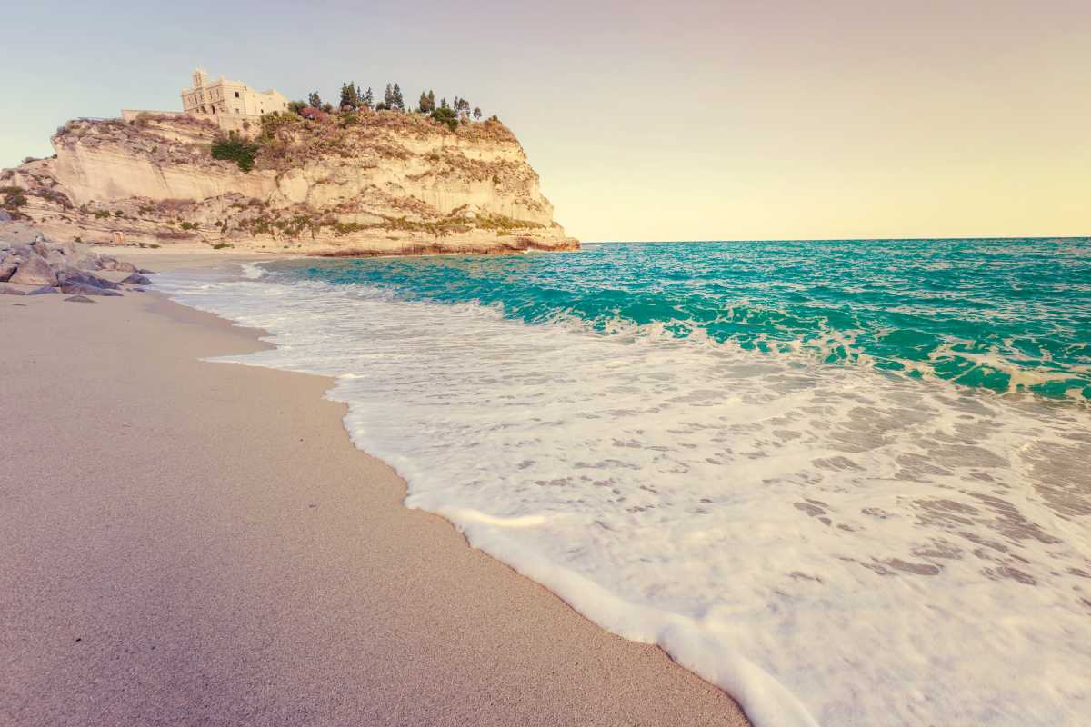 Vista panoramica dall’alto delle spiagge di Tropea, sabbia bianca, mare turchese, scogliere e Santuario dell’Isola sullo sfondo